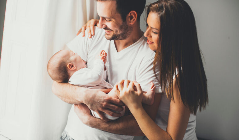 View at Happy family with newborn baby by the window
